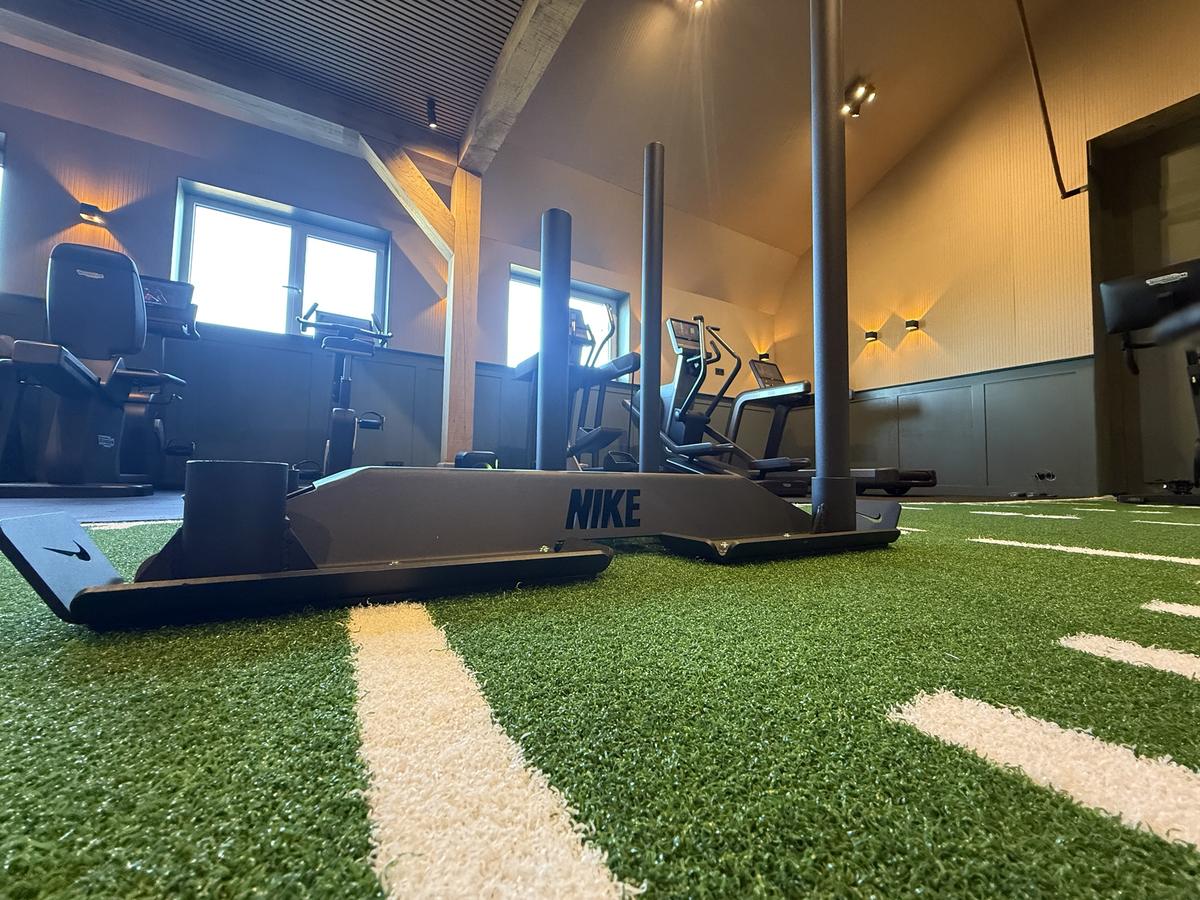 Een sled op de groene sprintbaan met cardioapparaten op de achtergrond
